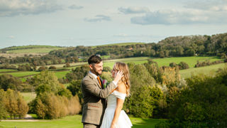 Wedding couple smiling with countryside background and white peacock